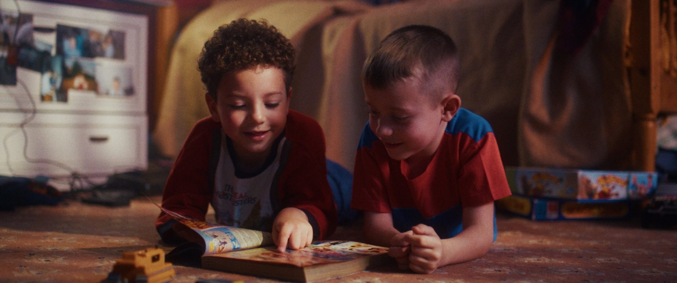 Two boys reading on a bedroom floor, a still from the RTS-nominated music video Still Hear You, shot by Lou Murrall